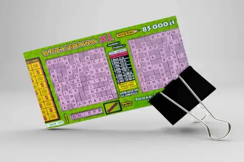 Zdrapka z krzyżówką XL z nagrodą 85 000 zł, przytrzymana przez czarny klips biurowy.