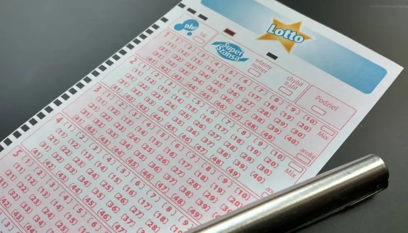 Kupon gry Lotto z zaznaczonymi polami i długopisem.