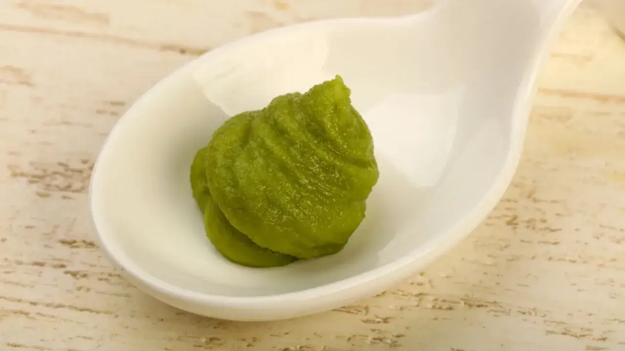 Zielony chrzan krzyżówka, czyli pasta wasabi, w białej miseczce. Ostry dodatek do sushi.